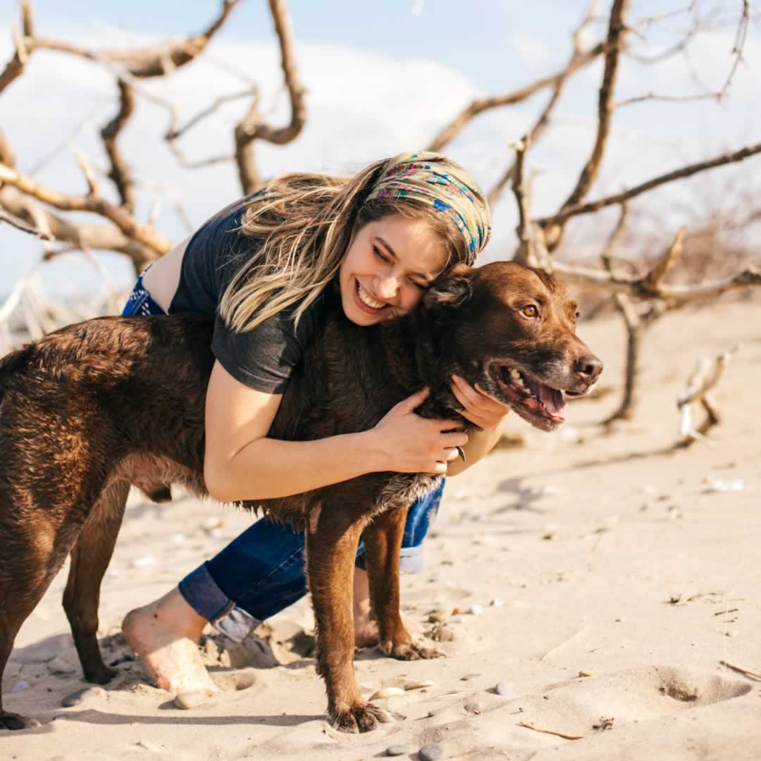A woman hugging her Labrador dog in what appears to be the desert.
